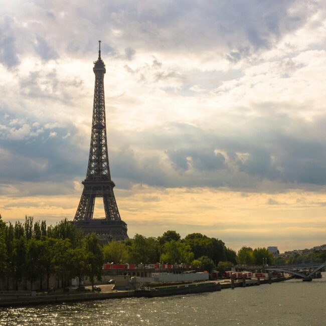 Stunning view of the Eiffel Tower at sunset with the River Seine and lush green trees.
